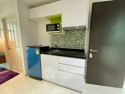 Modern compact kitchen with sleek cabinetry and mosaic backsplash in a cozy apartment.