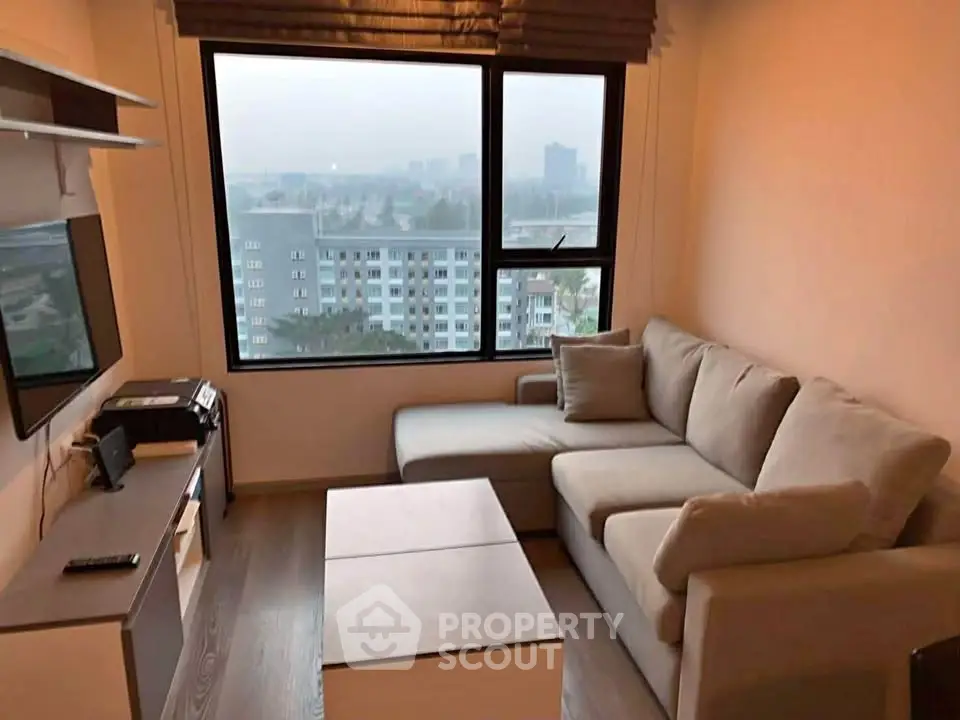 Cozy living room with modern sofa and city view from large window.