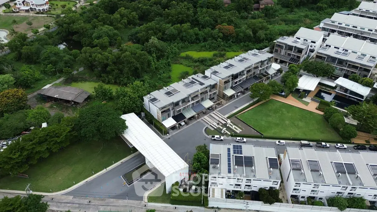 Aerial view of modern residential complex with lush greenery and solar panels.