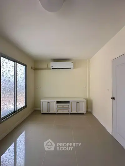 Spacious unfurnished room with air conditioning and large window, perfect for customization.