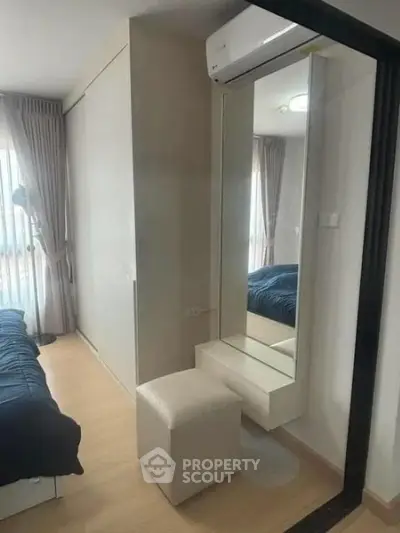 Modern bedroom with sleek design, featuring a large mirror, air conditioning, and natural light.