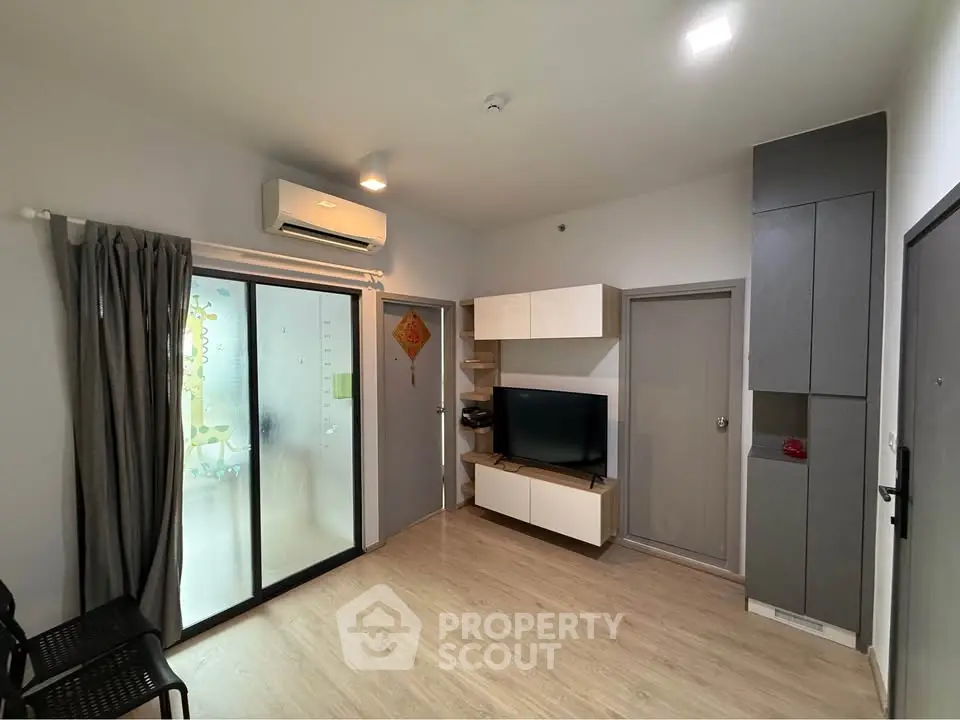 Modern living room with sleek design, featuring a wall-mounted TV, air conditioning, and sliding glass doors.