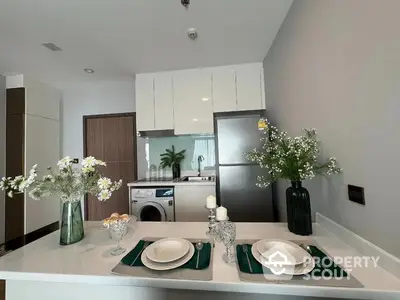 Modern kitchen with open layout, featuring stainless steel appliances, white cabinetry, and a neatly set dining counter.