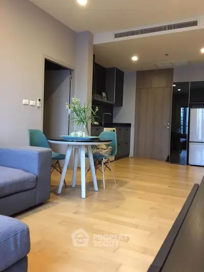 Modern living room with open kitchen, stylish furniture, and wooden flooring in a cozy apartment.