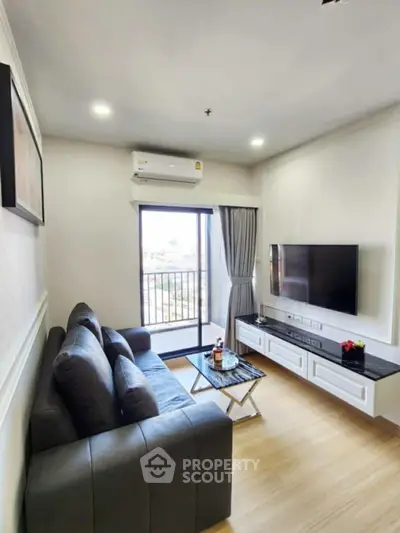 Modern living room with sleek furniture and balcony view, featuring a wall-mounted TV and air conditioning.