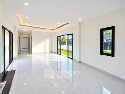 Spacious modern living room with large windows and garden view, perfect for family gatherings.
