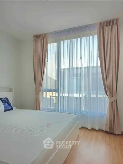 Bright bedroom with large window and elegant curtains, showcasing natural light and cozy ambiance.