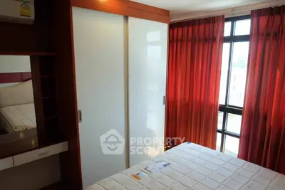 Cozy bedroom with large window and red curtains, featuring a modern wardrobe and comfortable bed.