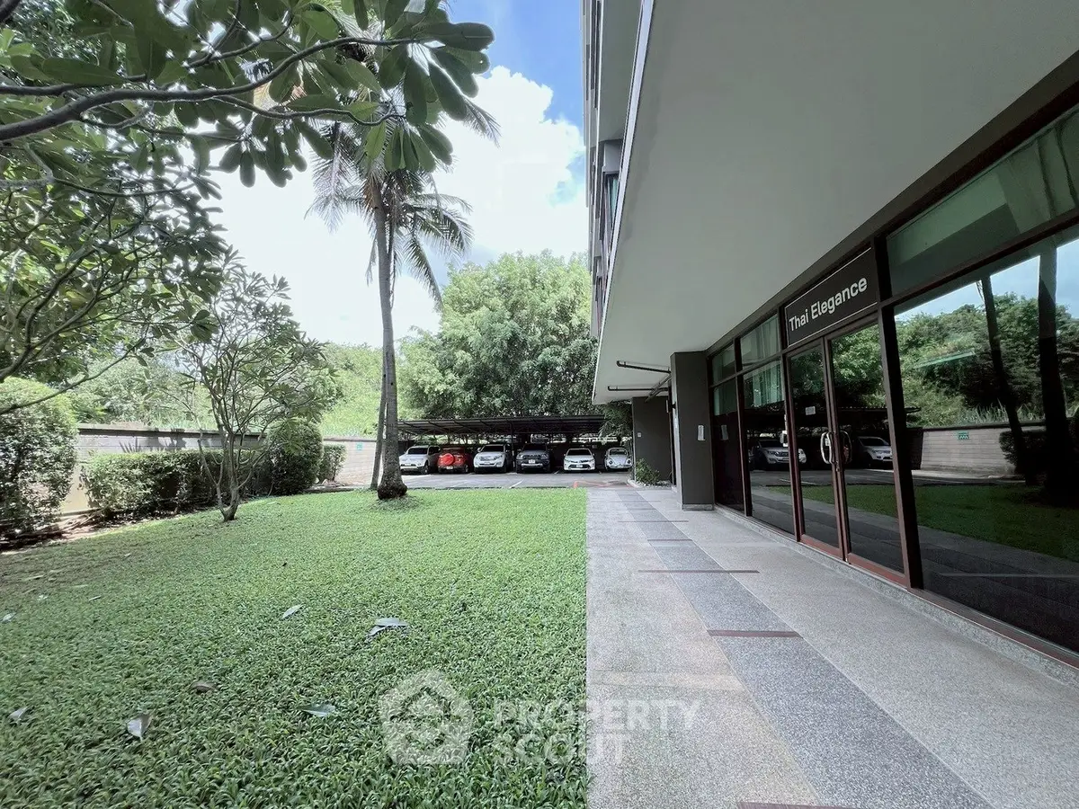 Elegant building exterior with lush garden and parking area, perfect for serene living.