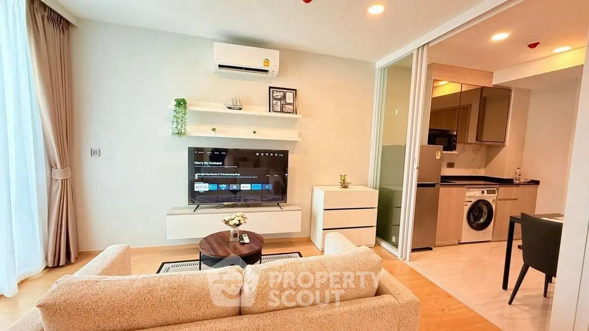Modern living room with open kitchen, featuring cozy sofa and wall-mounted TV, ideal for urban living.