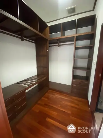 Spacious walk-in closet with wooden flooring and ample storage space.