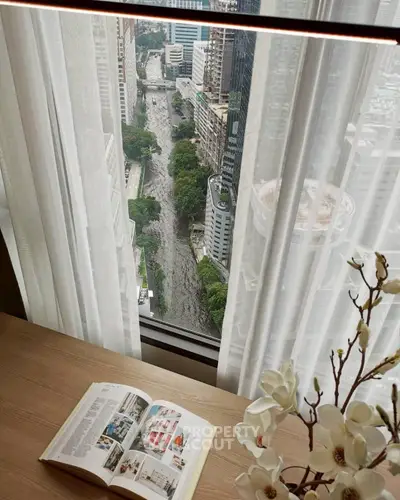 Stunning high-rise view from a modern apartment window with cityscape and open book on a wooden table.
