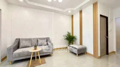 Modern living room with stylish gray sofa and ottoman, complemented by a chic side table and indoor plant.