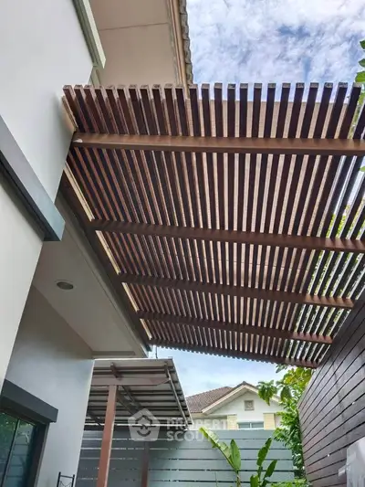 Modern house exterior with stylish wooden pergola and lush greenery