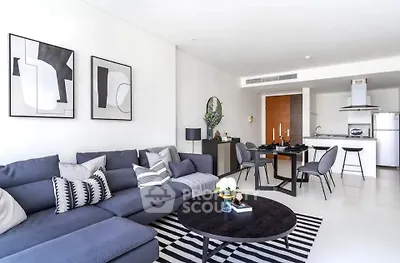Modern living room with stylish decor and open kitchen layout, featuring a sleek sectional sofa and contemporary dining area.