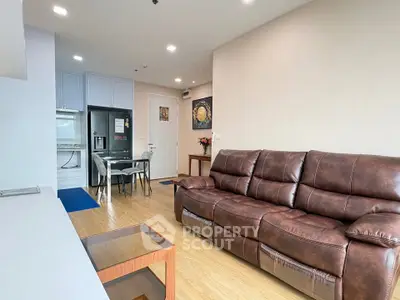 Modern living room with leather sofa and open kitchen layout in a cozy apartment.