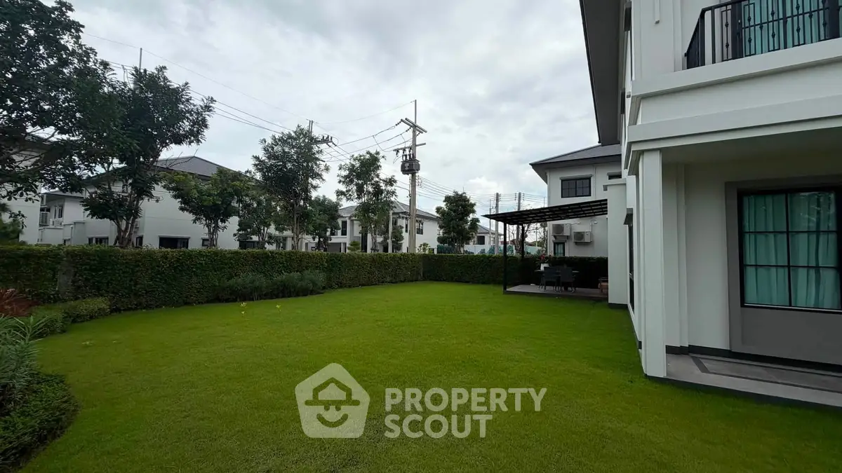 Spacious backyard with lush green lawn and modern house exterior in a serene neighborhood.