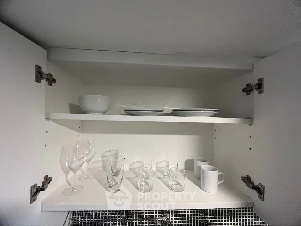 Modern kitchen cabinet with glassware and dishes neatly arranged on shelves.