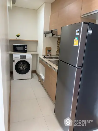 Compact modern kitchen with washing machine and stainless steel fridge