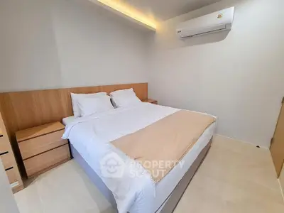 Modern bedroom with minimalist design and air conditioning unit, featuring a cozy bed and wooden accents.