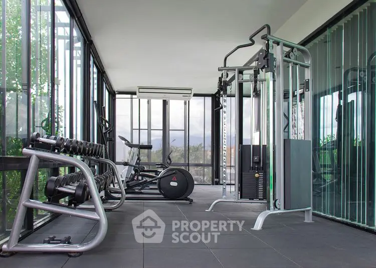 Modern home gym with exercise equipment and glass walls offering scenic views.