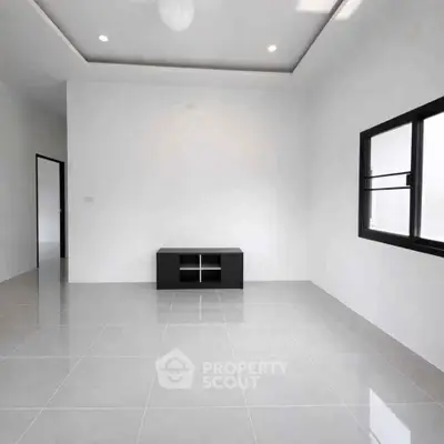 Spacious minimalist living room with sleek tile flooring and modern window design.
