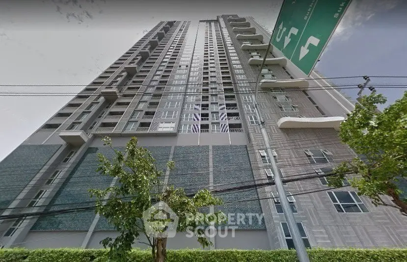 Modern high-rise building exterior with lush greenery and clear sky