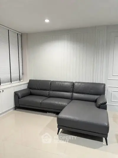 Modern living room with sleek gray sectional sofa and elegant paneling, perfect for stylish comfort.