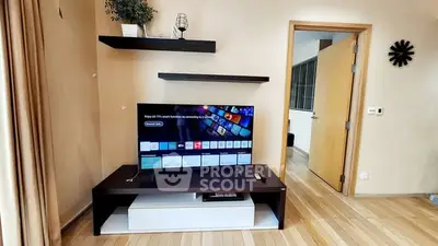 Modern living room with smart TV and wooden flooring, showcasing minimalist decor.