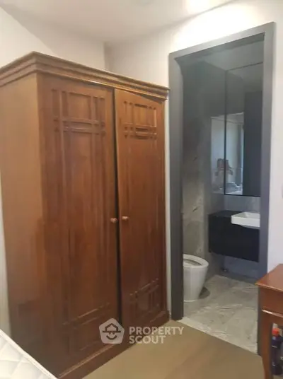 Cozy bedroom with wooden wardrobe and ensuite bathroom, perfect for modern living.