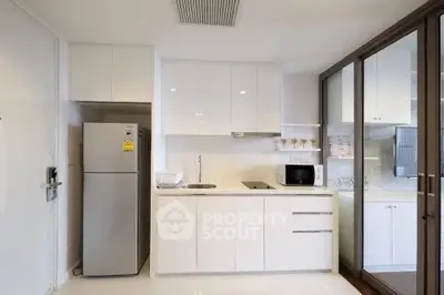Modern kitchen with sleek white cabinets and stainless steel appliances in a contemporary apartment.