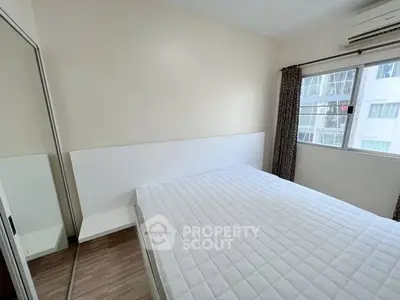 Bright bedroom with large window and mirrored closet in modern apartment.