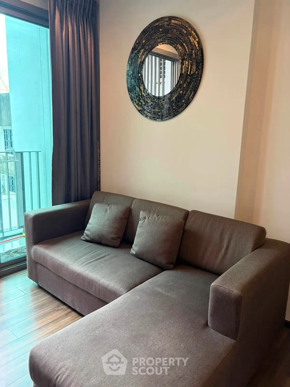 Modern living room with stylish sofa and decorative mirror, featuring a cozy ambiance and natural light.