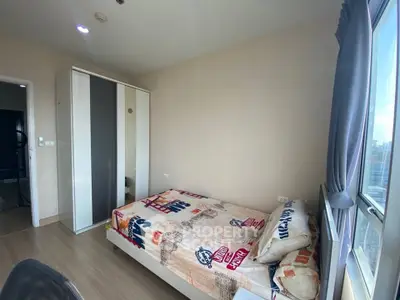 Cozy bedroom with large window and modern wardrobe in a bright apartment.