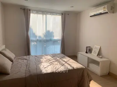 Cozy bedroom with natural light, featuring a comfortable bed and modern air conditioning unit.