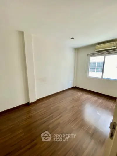 Spacious empty room with wooden flooring and large window