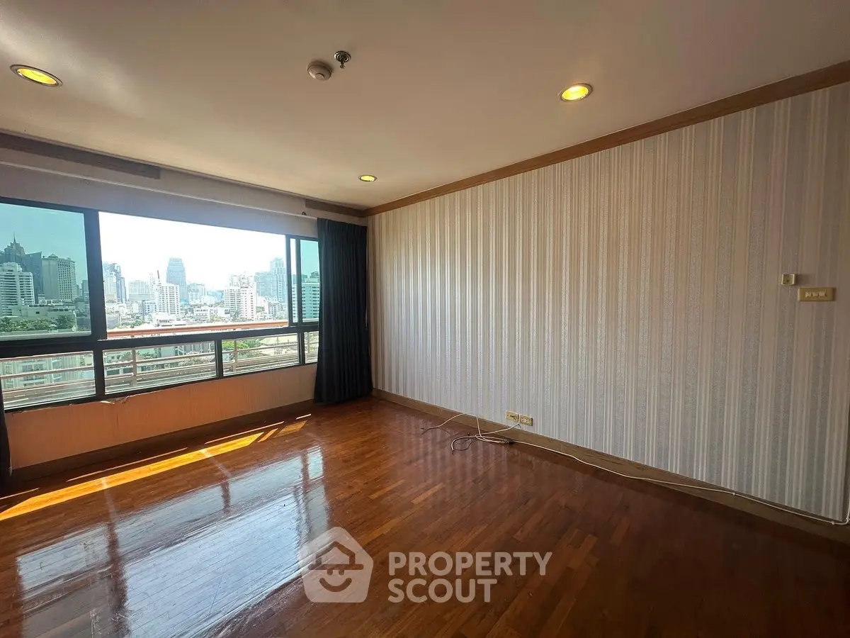 Spacious empty room with city view and wooden flooring