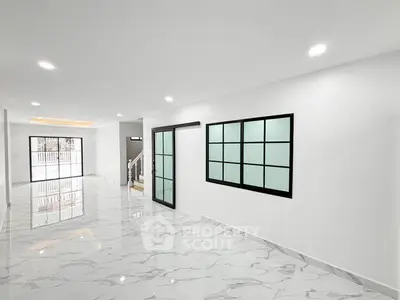 Spacious modern living room with marble flooring and large windows.