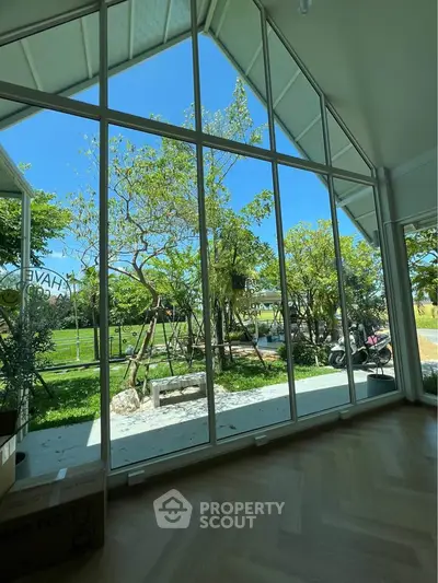 Spacious living room with floor-to-ceiling windows offering a stunning garden view.