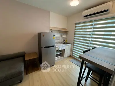Modern compact kitchen with fridge and dining area in cozy apartment
