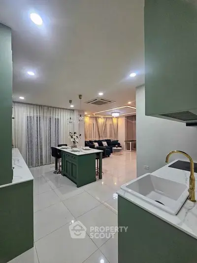 Modern open-layout kitchen and living room with elegant green cabinetry and stylish decor.