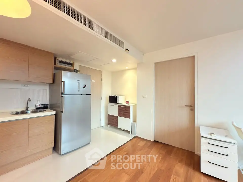 Modern kitchen with sleek appliances and wooden cabinetry in a bright apartment.