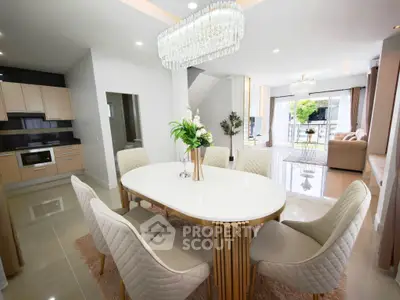 Luxurious open-plan living and dining area with elegant chandelier and modern kitchen.