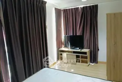 Cozy bedroom with TV and dark curtains, perfect for relaxation.