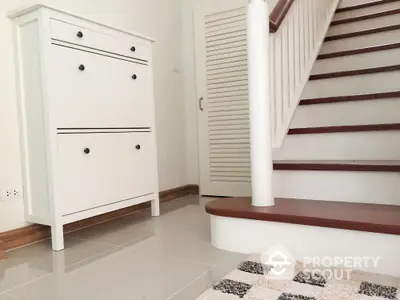 Stylish interior with modern staircase and sleek storage unit in a contemporary home.