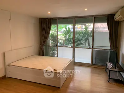 Spacious bedroom with large windows and modern furnishings in a serene setting.