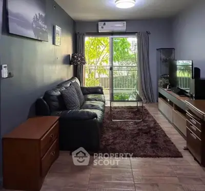 Cozy living room with modern decor, large window, and lush garden view.