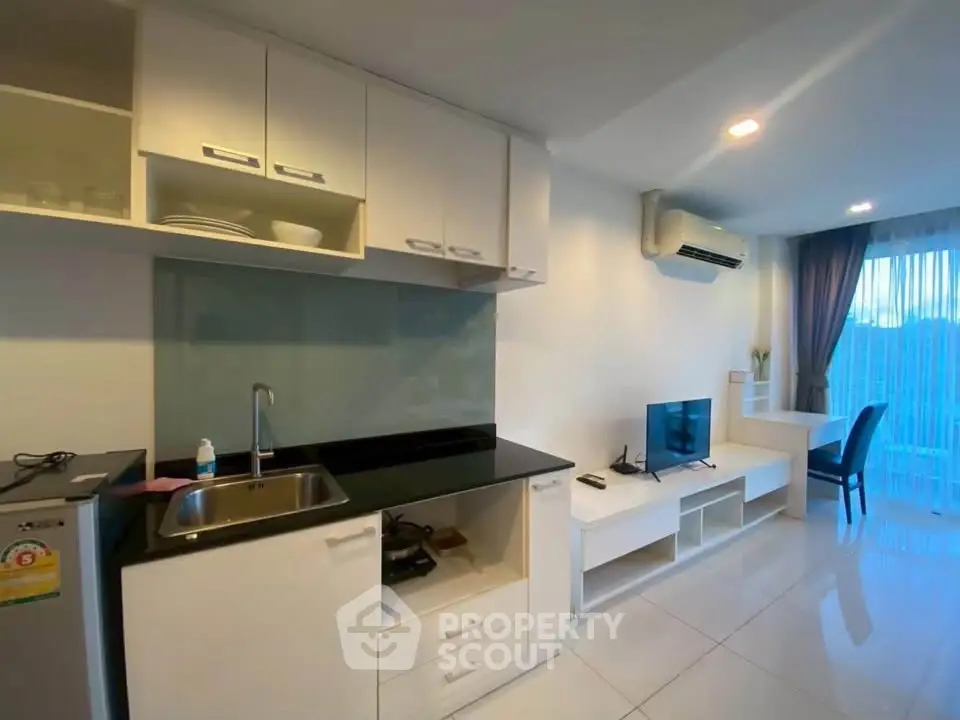 Modern studio apartment with sleek kitchen and cozy living area, featuring large windows and natural light.
