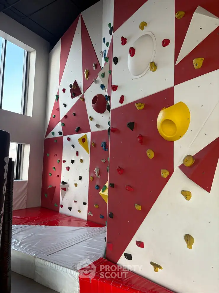 Modern indoor climbing wall with colorful holds in a bright gym space.