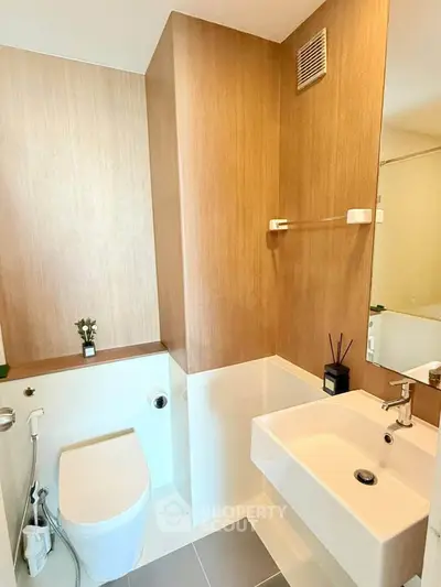 Modern bathroom with sleek fixtures and wooden accents in a stylish apartment.
